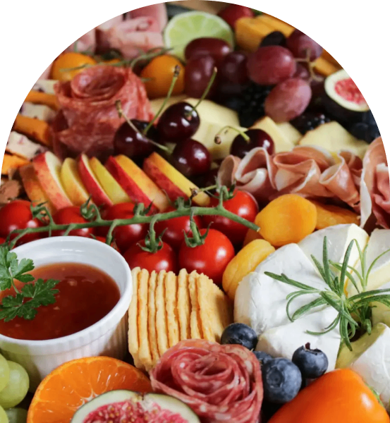 A colorful charcuterie board with meats, cheeses, fruits, and dips.