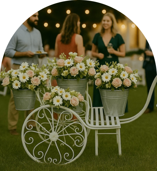 Decorative flower arrangement in a white metal cart at an outdoor event.
