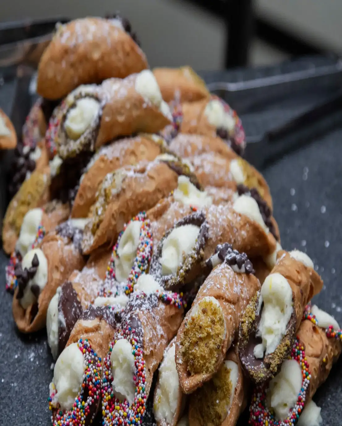 A stack of powdered sugar-dusted pastries with cream and fruit filling.