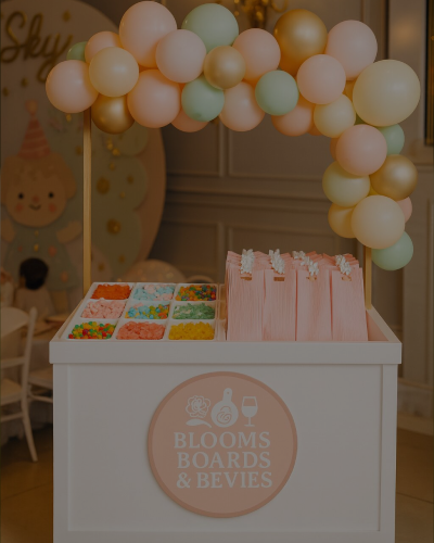 A pastel-themed dessert table with balloons and treats for a birthday party.